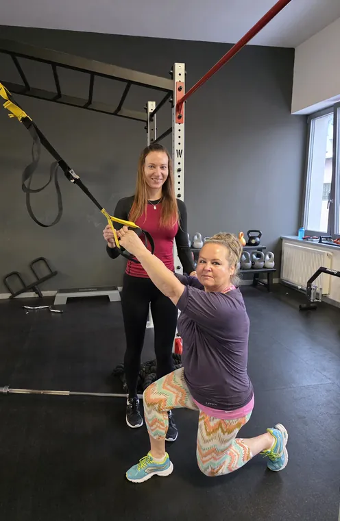 Trénerka vedie klientku pri cvičení s TRX popruhmi